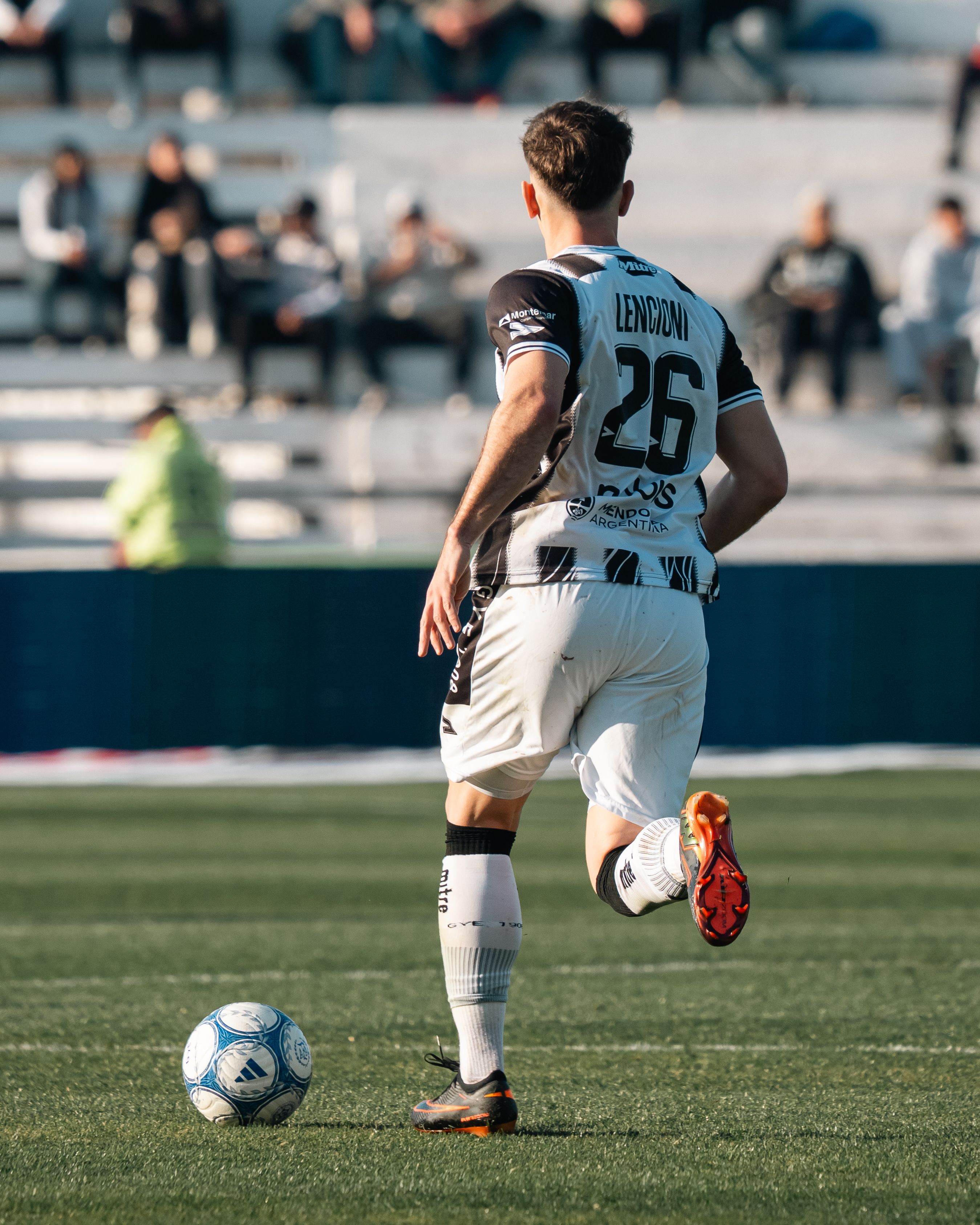 Action-packed soccer scene with a player dribbling towards the goal on a sunny day.