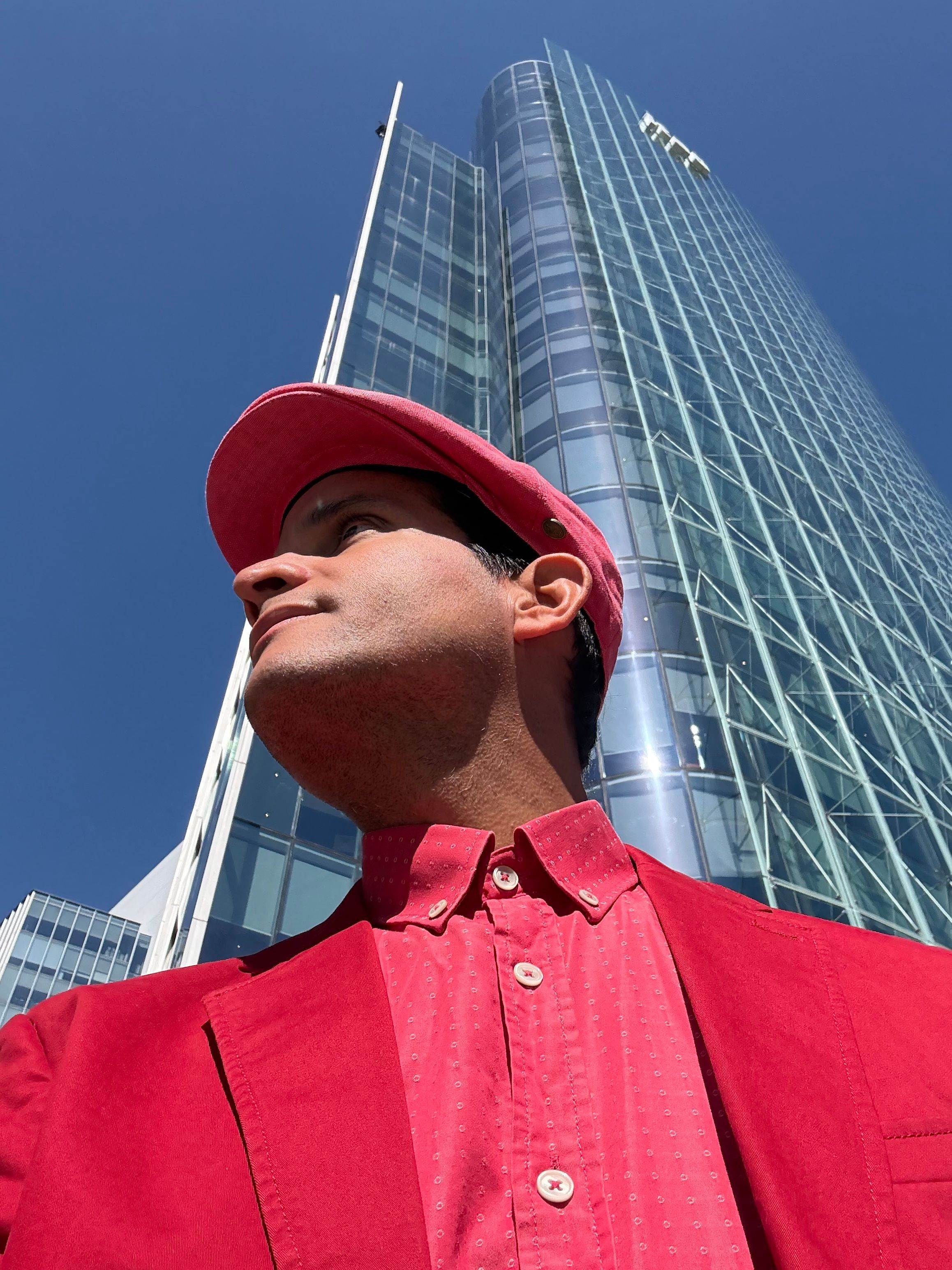 A man in red looking up at a modern skyscraper in Las Condes, Chile.