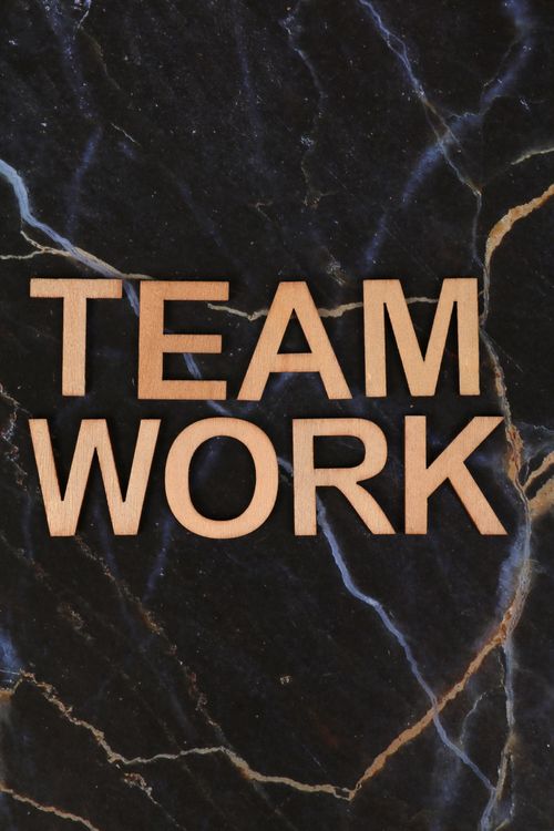 Free Inspiring teamwork message displayed with wooden letters on a dark marble background. Stock Photo
