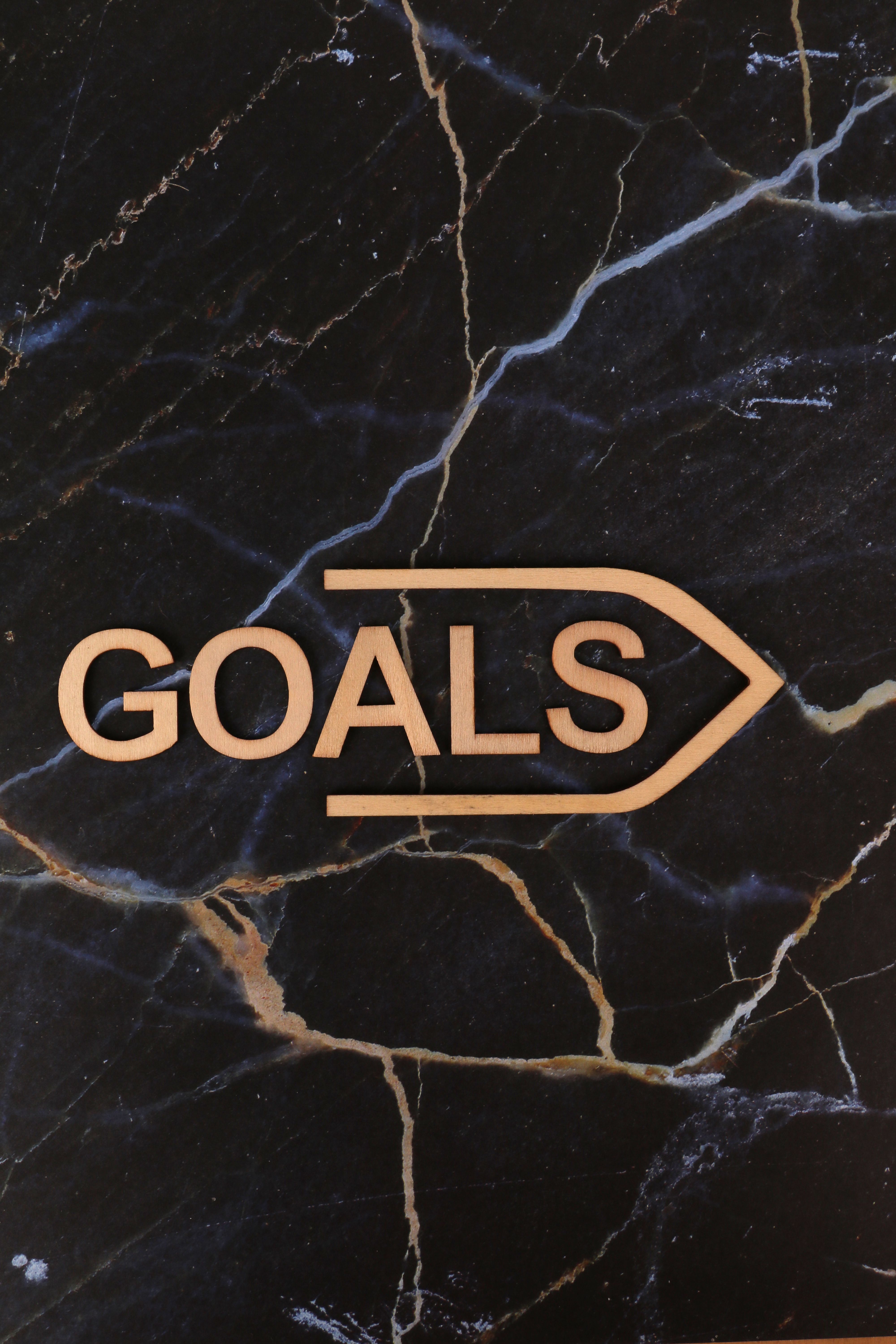 Inspirational text 'Goals' with arrow on a marble background, perfect for motivation.