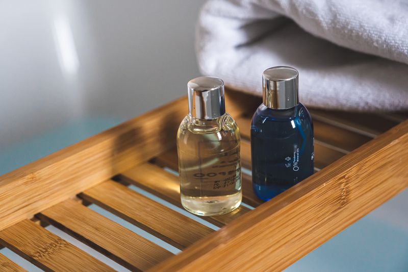 Two elegant toiletries bottles on a bamboo tray in a serene bathroom setting.