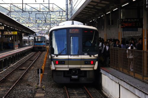 Free Busy Kyoto station platform with JR West commuter trains amid passengers in Japan. Stock Photo