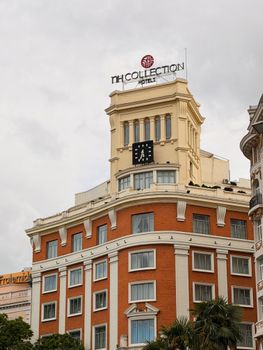 Historic NH Collection Hotel building with iconic clock tower in Madrid, Spain.