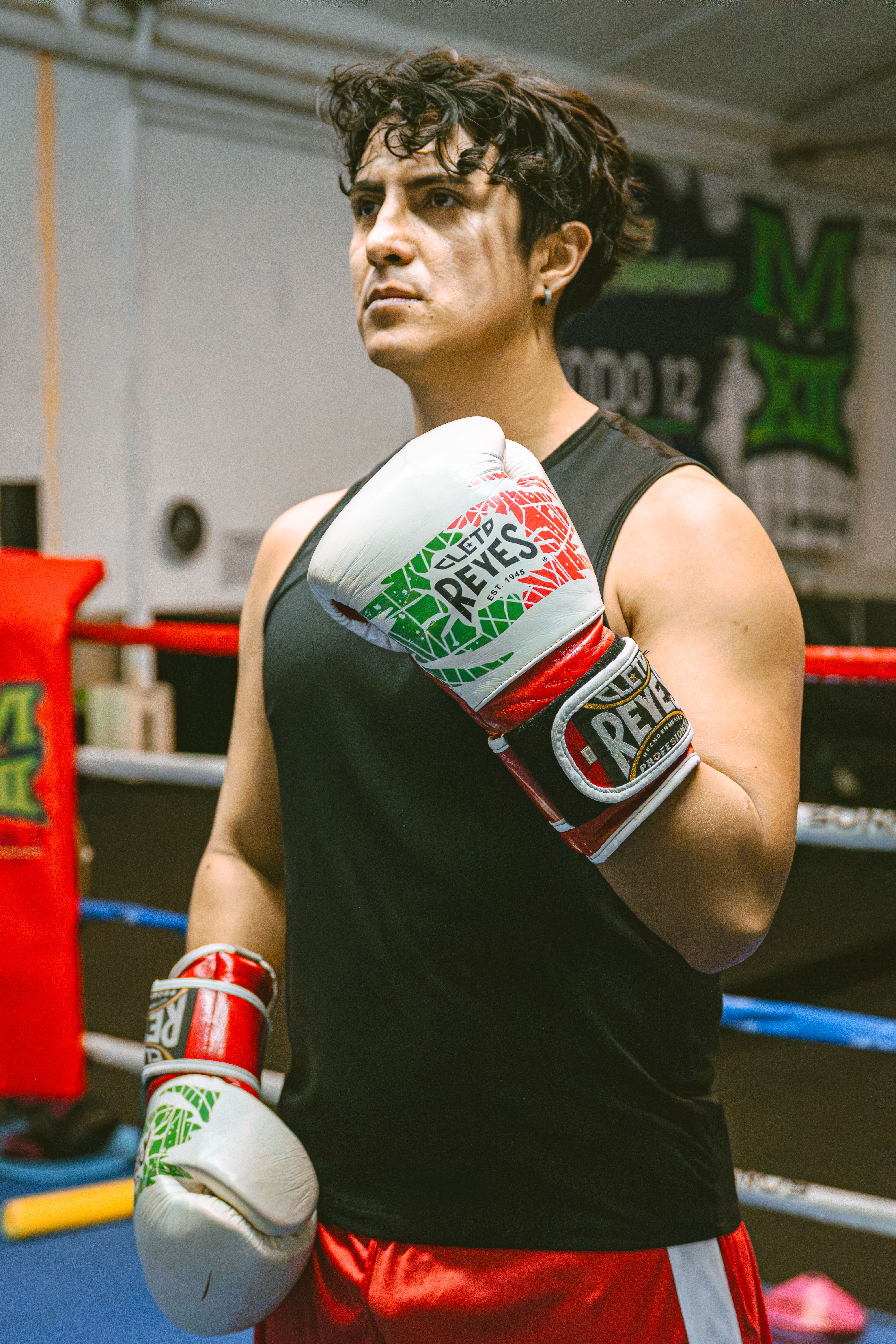 Boxer in gym holding gloves, preparing for training session indoors in Buenos Aires.