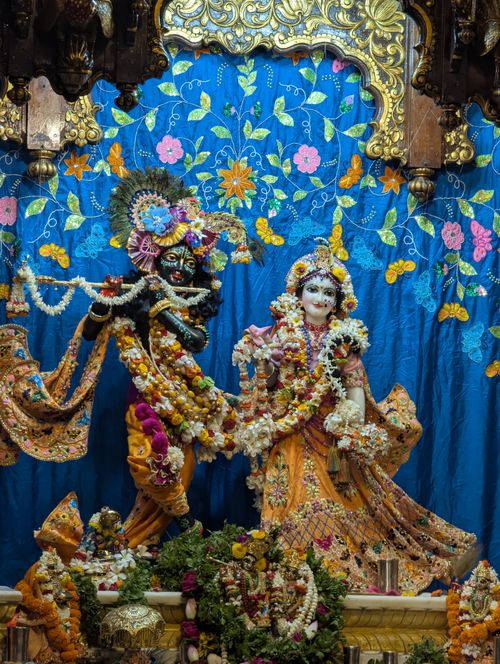 Free Ornate idol of Krishna and Radha adorned with vibrant flowers and intricate clothing. Stock Photo