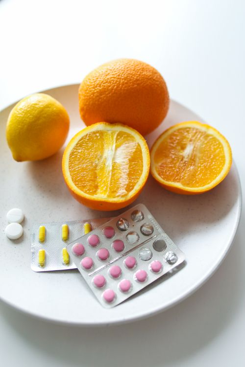 Free A close-up of oranges and pills on a white plate, symbolizing health and nutrition. Stock Photo