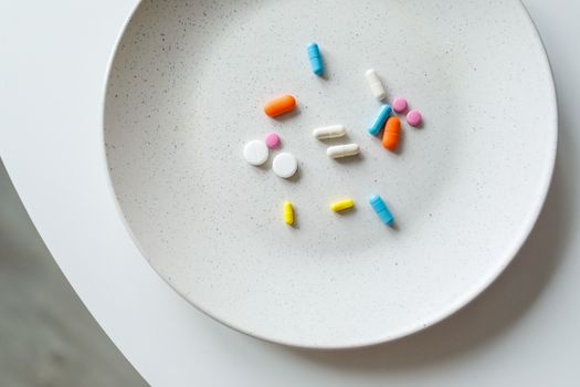 A variety of colorful medicine pills arranged on a white plate, symbolizing healthcare.