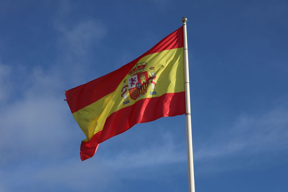 Una vibrante bandera española ondeando bajo un cielo azul despejado, simbolizando el orgullo nacional y el patriotismo.