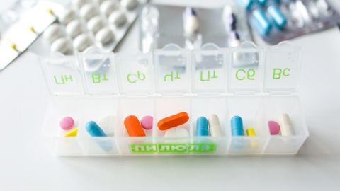 Colorful pills and capsules in a labeled weekly organizer for easy medication management.