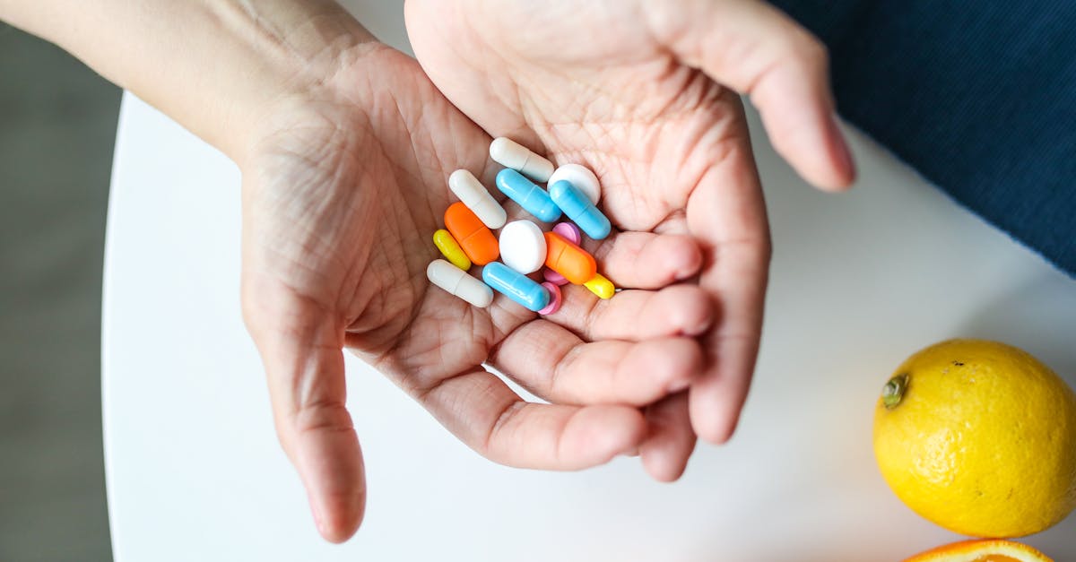 Close-up of hands holding multicolored pills with oranges, symbolizing health and nutrition. Close-up of hands holding multicolored pills with oranges, symbolizing health and nutrition.