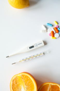 Digital and mercury thermometers with colorful pills and citrus fruits on white background. Health concept.