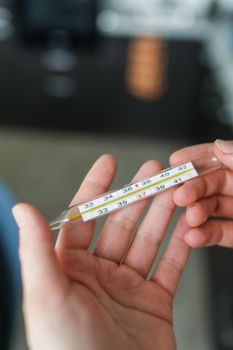 特写镜头中，手持玻璃温度计的手显示出高温
