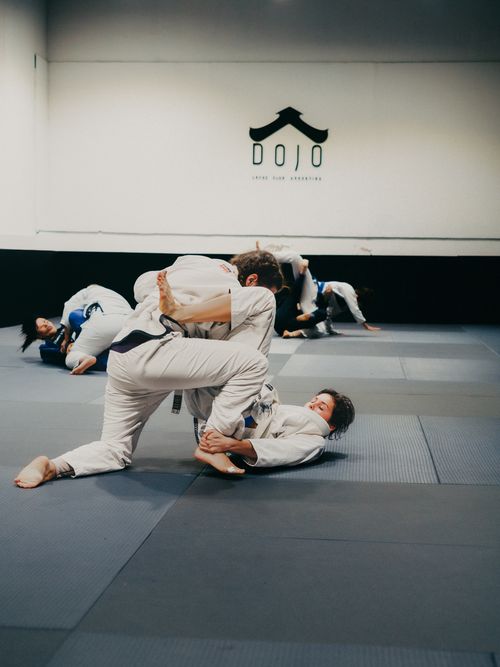 Free Adults practicing Brazilian Jiu-Jitsu in a dojo, showcasing grappling techniques and synergy. Stock Photo