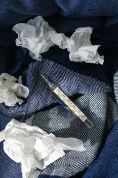 旧纸巾和温度计放在牛仔布上，象征着家里的疾病