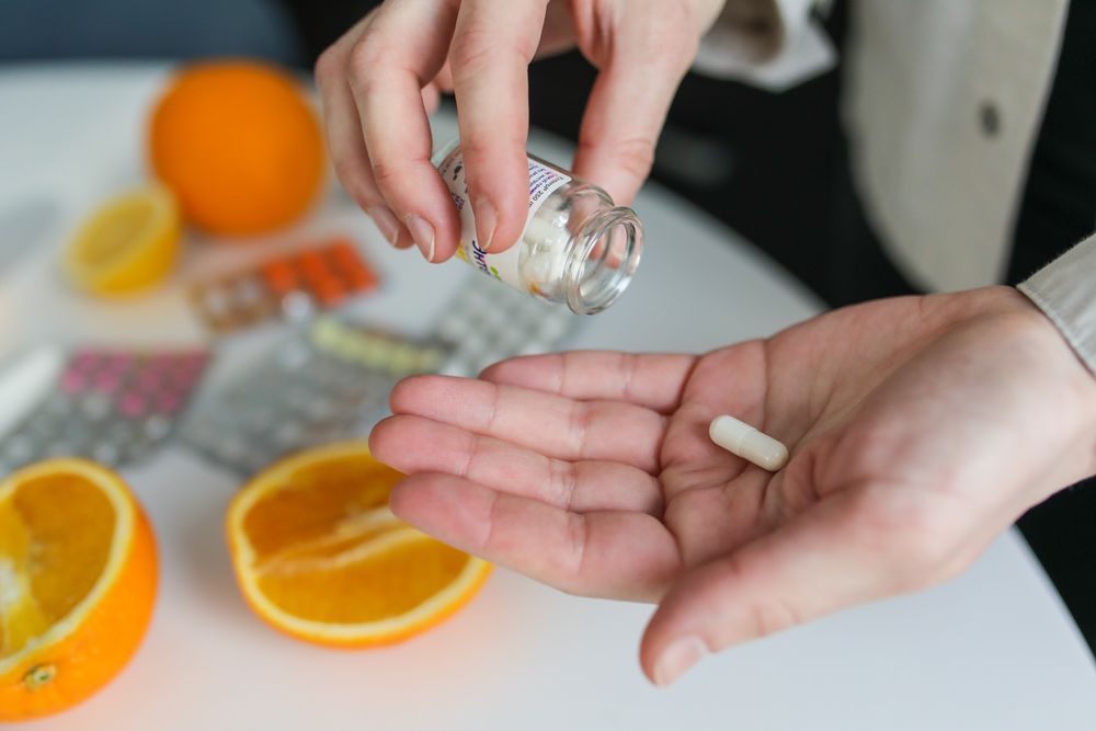 Medication capsules with a pill bottle and fresh oranges