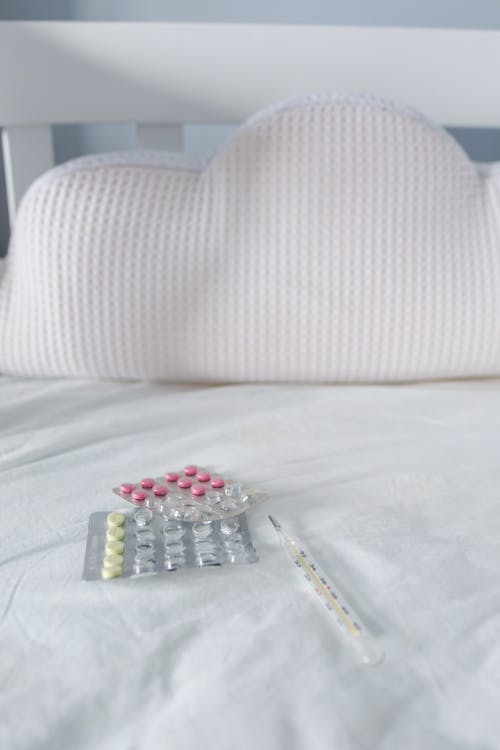Free Thermometer and Pills on Bed Stock Photo