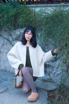Young woman enjoying a summer day in Nanjing park wearing chic attire and glasses.