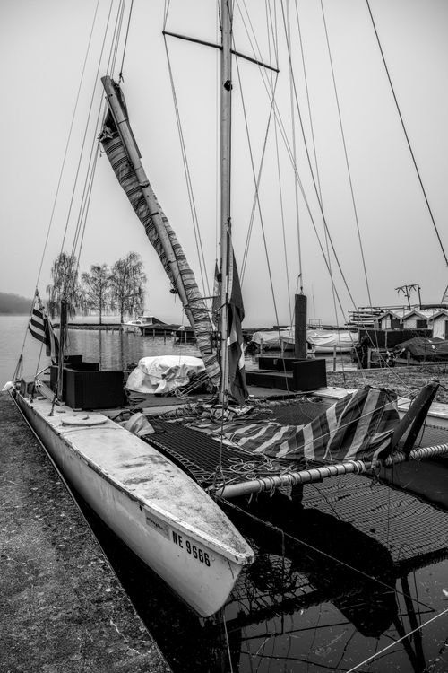 Free Rustic black and white photo of a sailboat moored at a foggy dock, evoking a serene atmosphere. Stock Photo