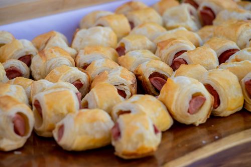Free Close-up of delicious homemade sausage rolls on a wooden tray, perfect for parties or snacks. Stock Photo