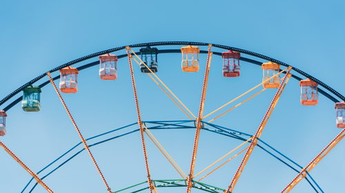 Free Vibrant ferris wheel with colorful cabins reaching into a cloudless blue sky. Stock Photo