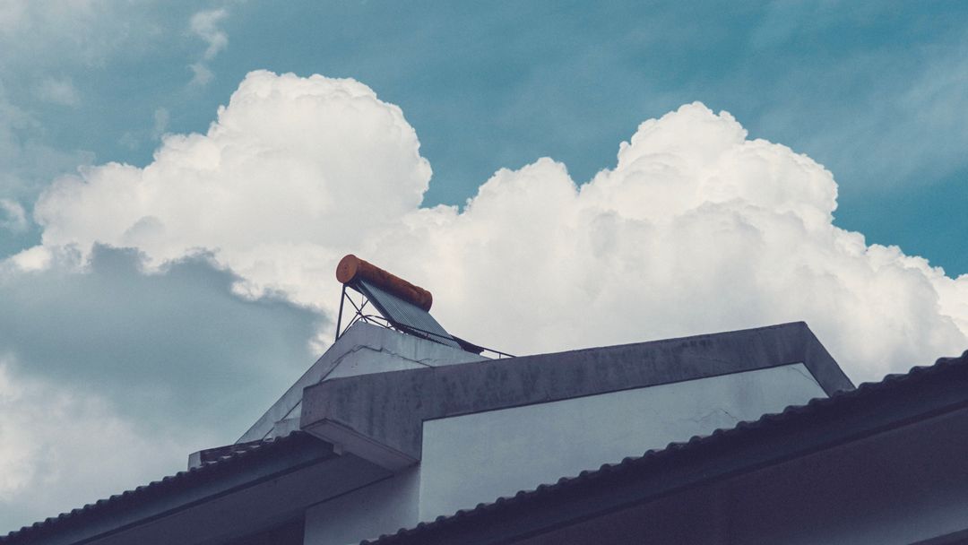 A solar water heater on a building rooftop against a cloudy sky
