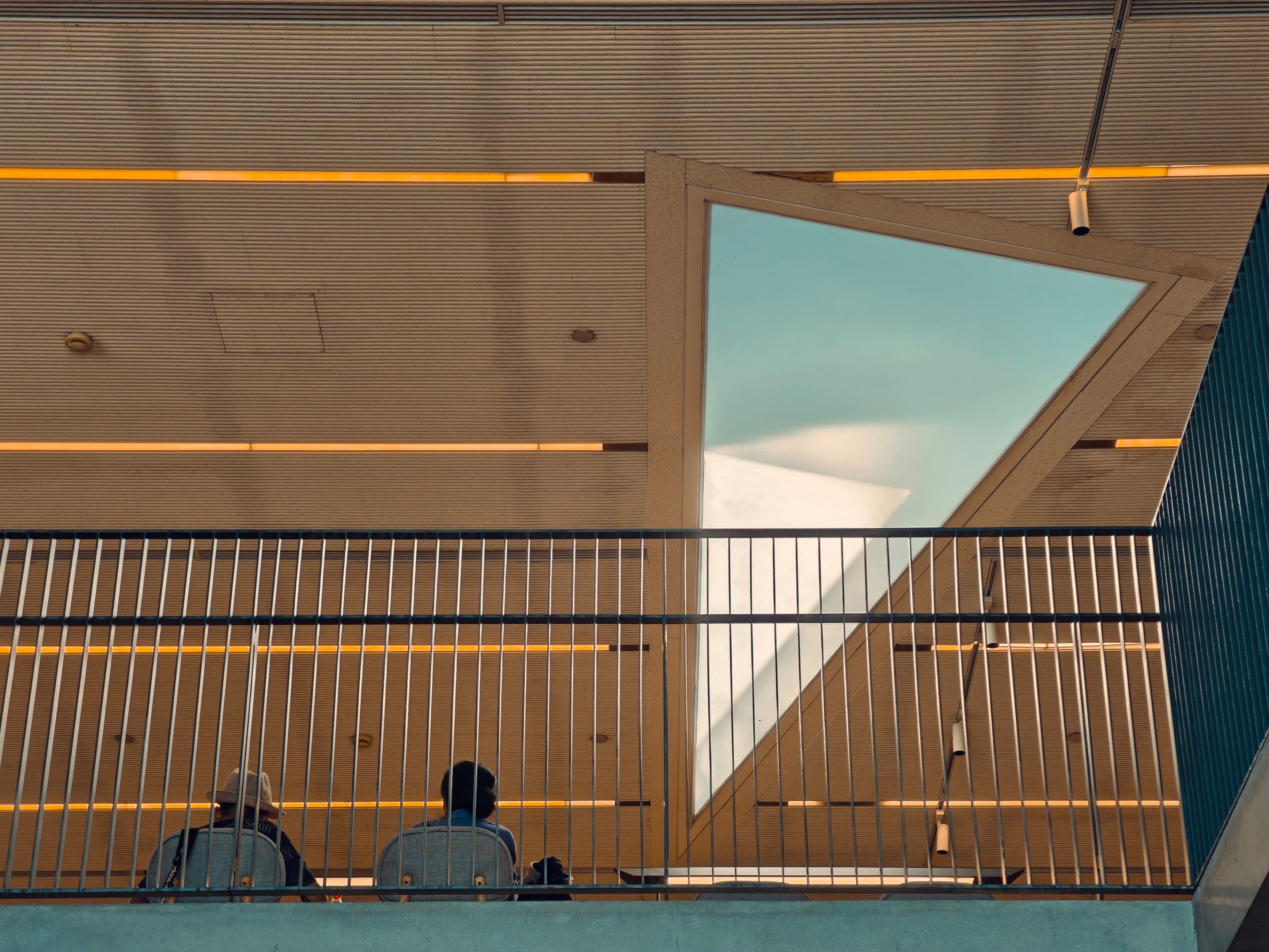 Interior de un edificio moderno con dos personas bajo una gran claraboya.