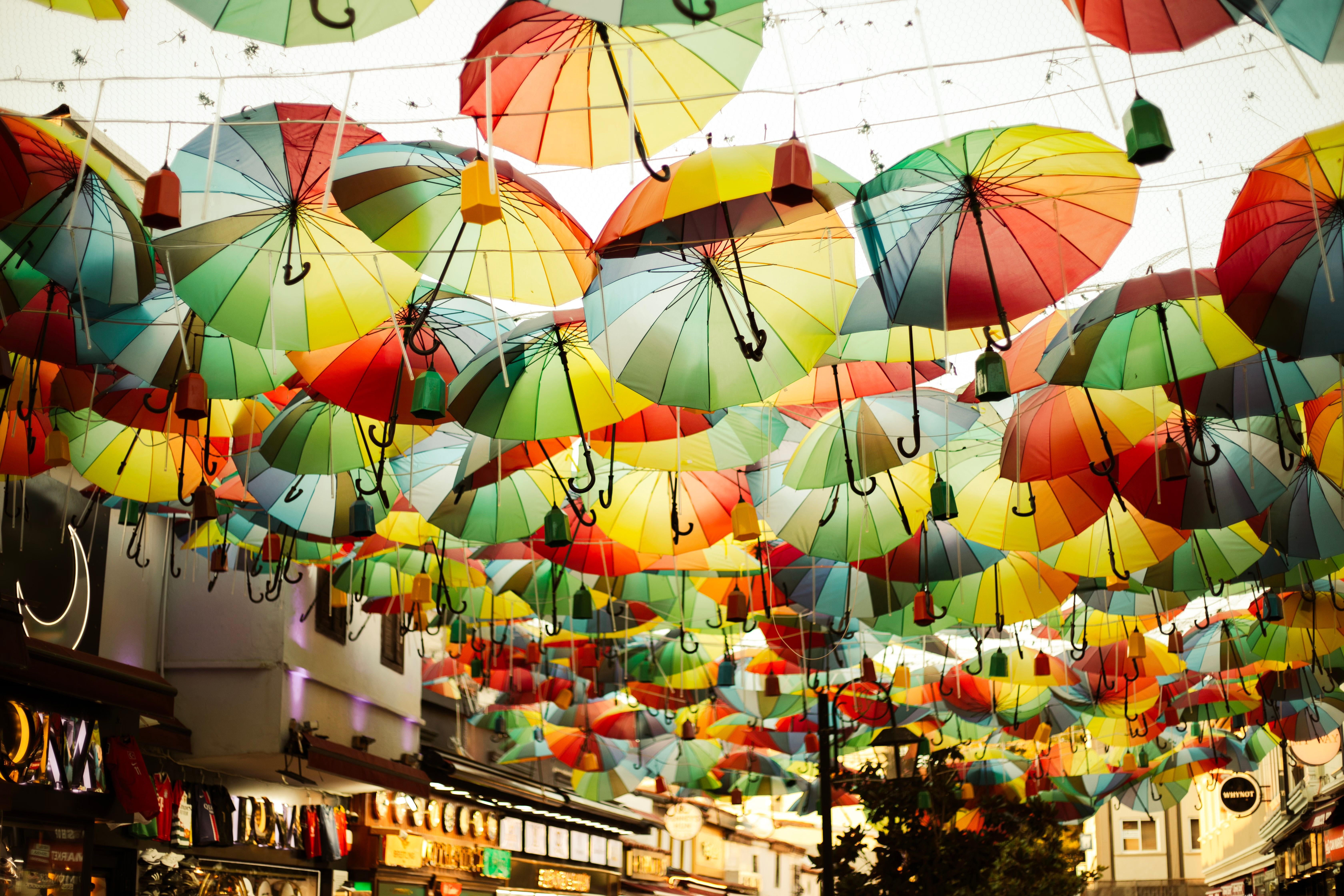 Colorful umbrellas create a vibrant canopy over a lively street scene, adding artistic flair.
