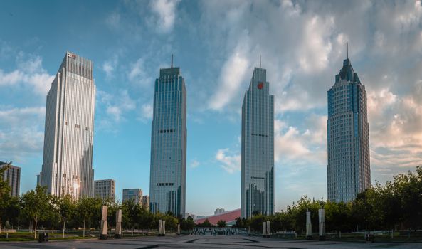 A vibrant cityscape featuring four modern skyscrapers against a bright sky.
