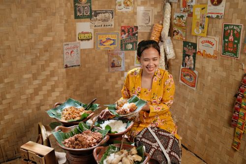 Free Smiling woman enjoying traditional Indonesian cuisine in a Jakarta eatery with vintage decor. Stock Photo