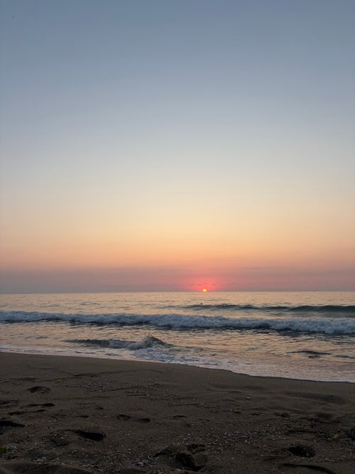 Free A tranquil beach scene with a gentle sunrise over the ocean, capturing the peaceful start of the day. Stock Photo