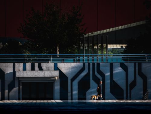 Free Silhouette of a person walking a dog in an urban setting, dramatic lighting and shadows. Stock Photo