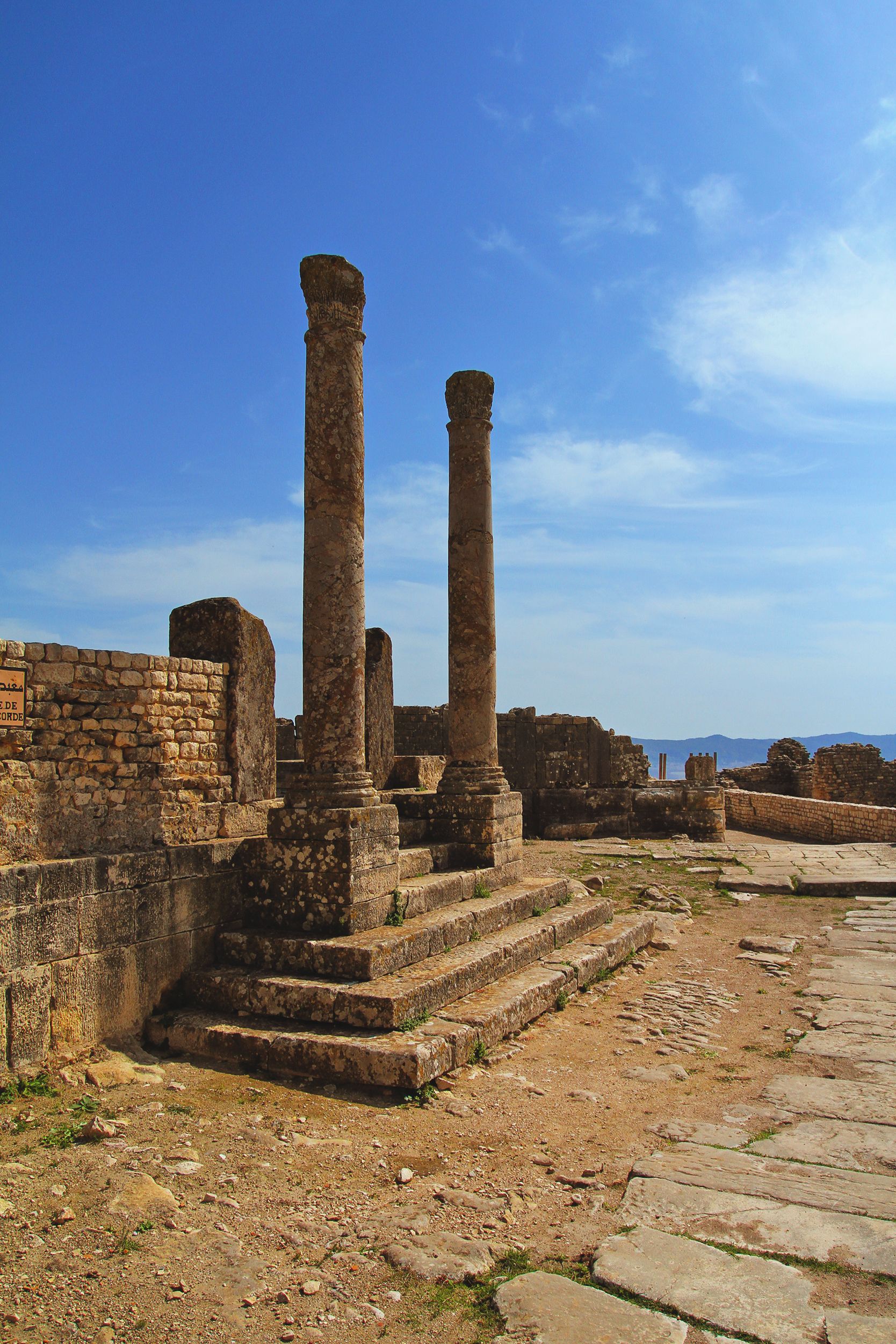 Explore the historic Roman ruins of Teboursouk, Tunisia, under a clear blue sky.