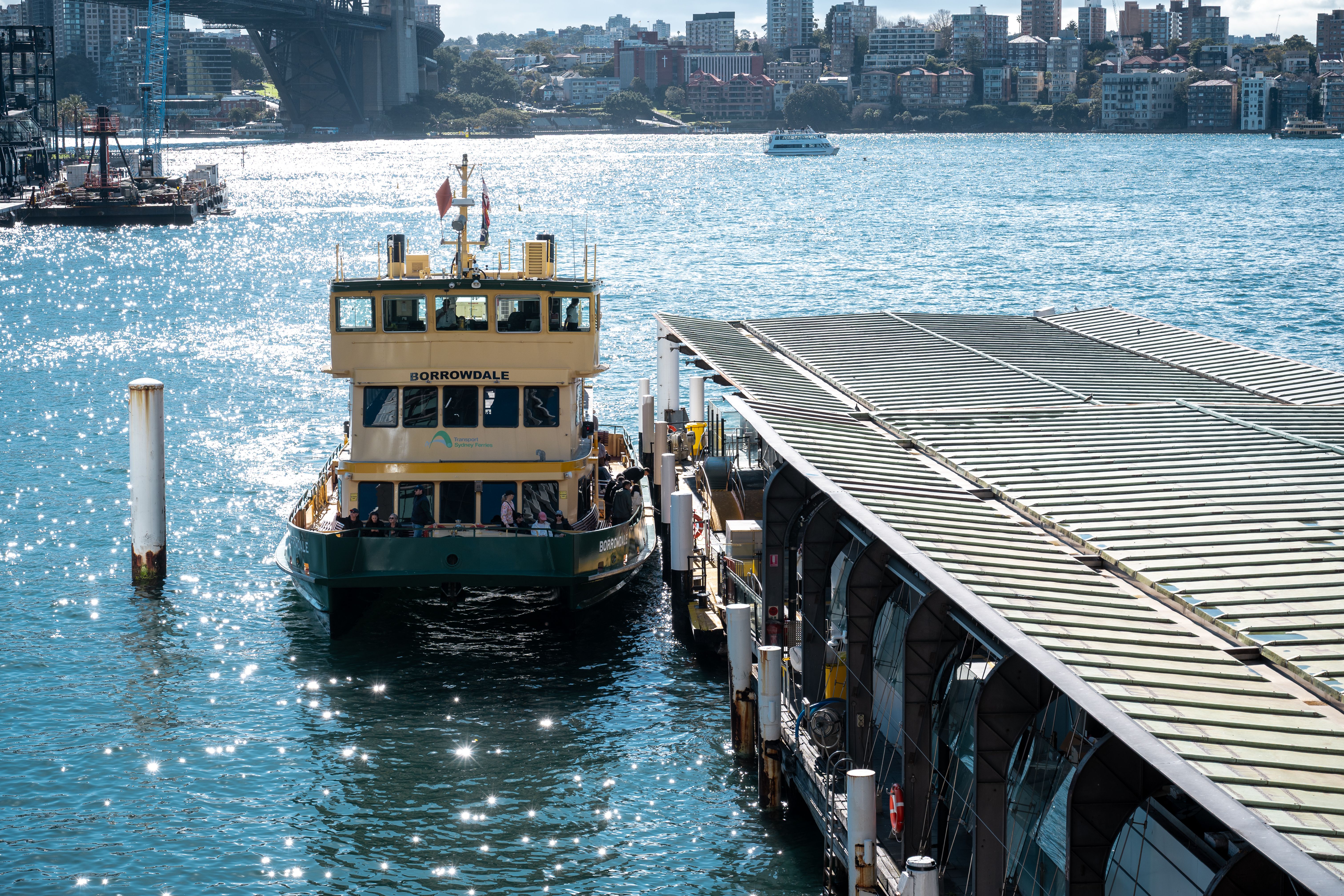 A scenic view of the Sydney Ferry at Circular Quay with the iconic Sydney Harbour Bridge in the background.