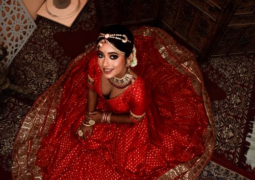 Free Captivating Indian bride in a red lehenga with intricate jewelry, seen from above. Stock Photo