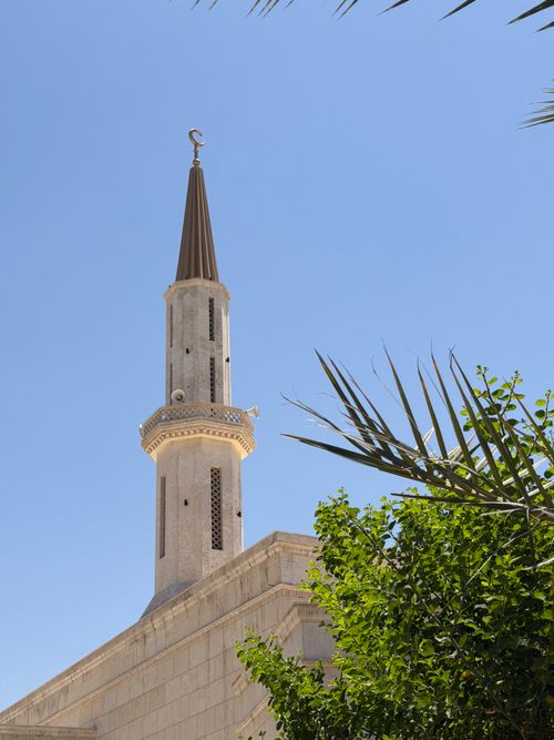 Free A beautiful minaret with intricate design against a bright blue sky, surrounded by lush greenery. Stock Photo