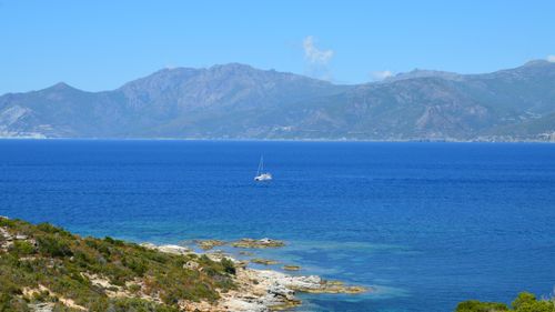 Free A serene view of a sailboat on the Mediterranean Sea near the coast of Corse, France. Stock Photo