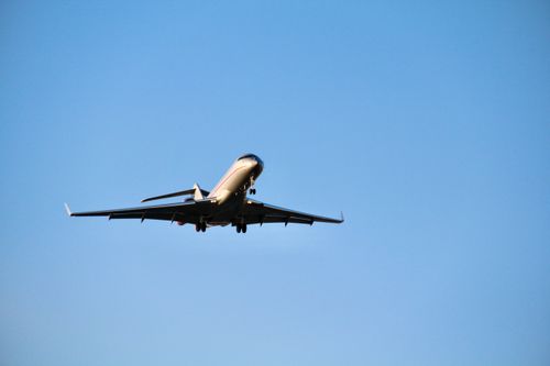 Free A sleek airplane flying against a bright blue sky, showcasing modern aviation. Stock Photo