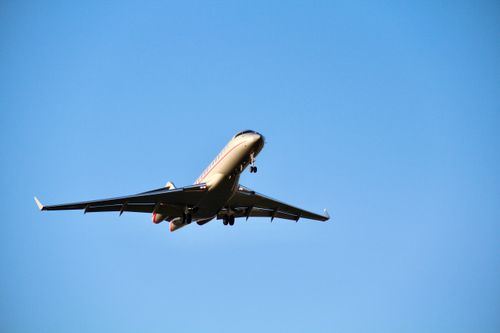 Free An airplane flying overhead against a clear blue sky, captured with a front view. Stock Photo