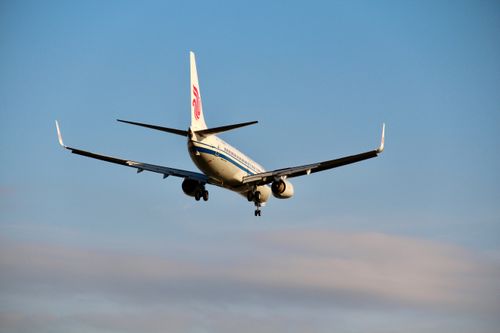 Free A commercial airliner approaching for landing, captured from behind against a clear blue sky. Stock Photo