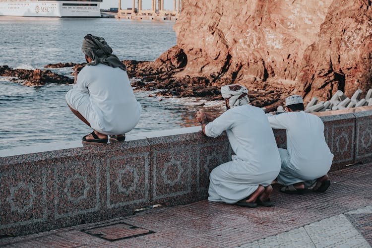 Arab Men In White Traditional Wear Praying On Embankment