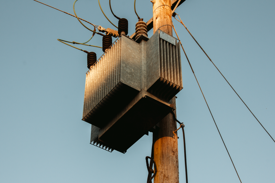 A detailed view of an electric transformer on a wooden pole during a warm sunset in Carrick-On-Shannon, Ireland.