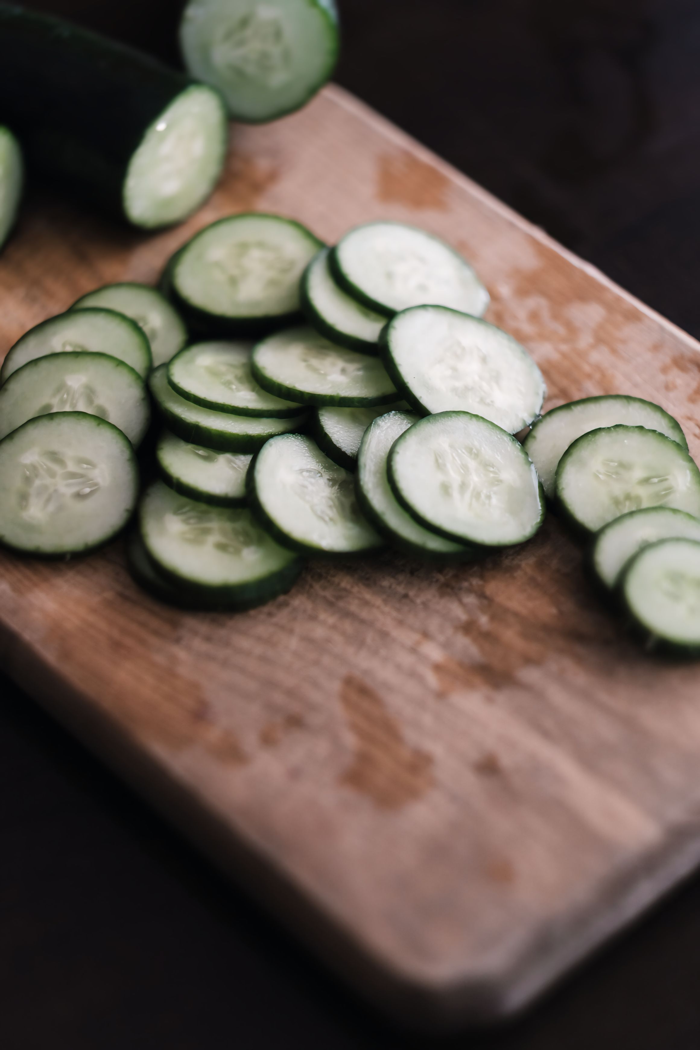 A handful of small, thin-skinned Persian cucumbers, whole and sliced into rounds, showing their tiny seeds and pale green flesh.