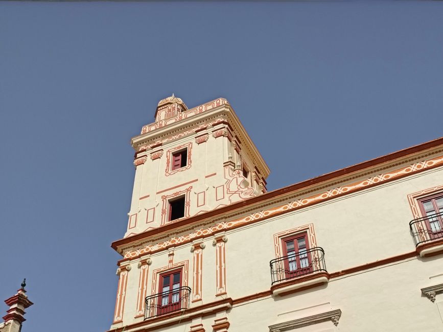 Edificio histórico ornamentado en Cádiz, España, que exhibe un diseño intrincado bajo un cielo despejado.