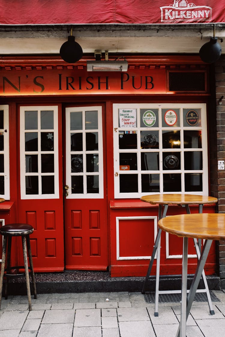 Entrance Of Pub With Red Door And Wooden Tables Nearby