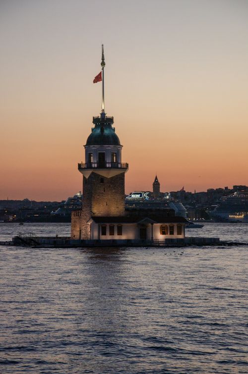 Free Stunning view of Maiden's Tower illuminated against a vibrant sunset on the Bosphorus in Istanbul, Turkey. Stock Photo
