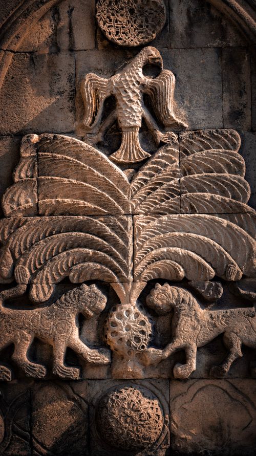 Free Historic stone relief depicting eagle, palm tree and lions with intricate carvings. Stock Photo