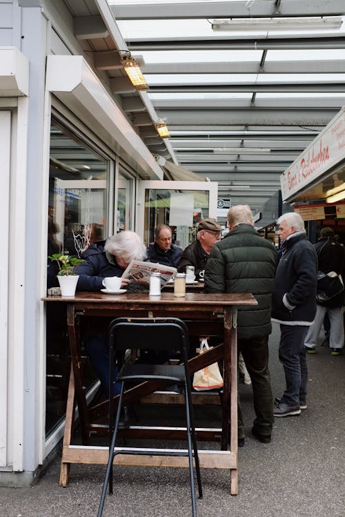 Visitors of local city market under roof standing at stall and talking while shopping on weekend