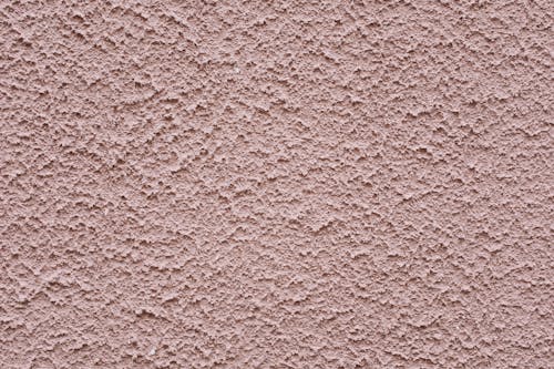 Simple background of uneven stucco pink wall surface of modern building in city