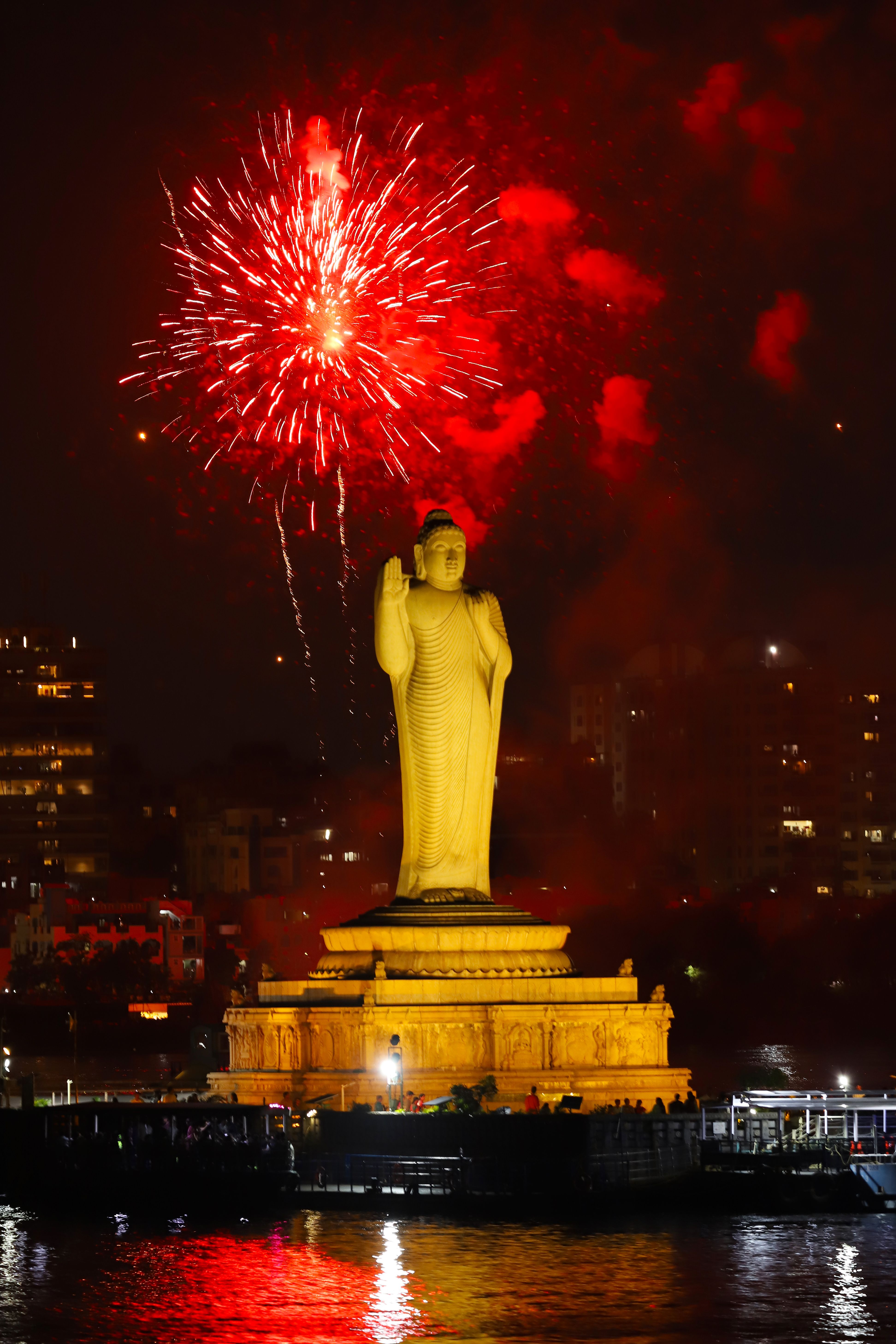 Stunning fireworks illuminate the Buddha statue at night, creating a dramatic and serene scene.