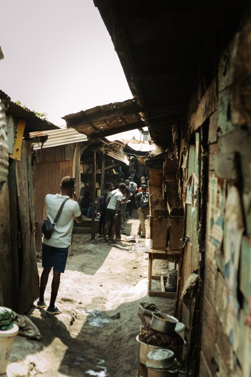 Free People walking through a narrow, lively marketplace alley with rustic wooden structures. Stock Photo